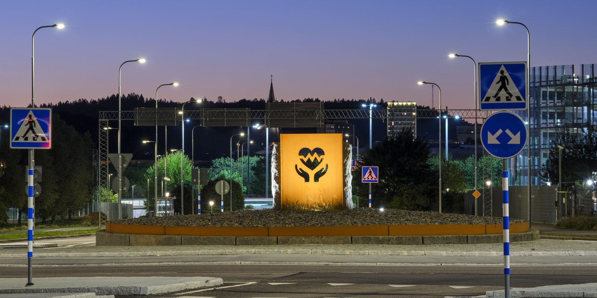 Roundabout and road at blue hour, lit by evenly spaced street-light columns